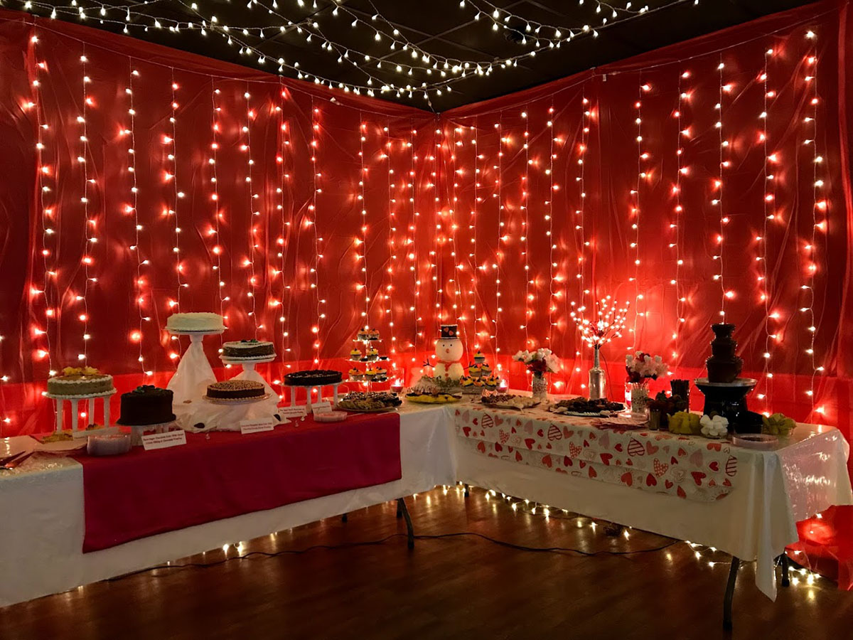 Wedding Desert table at Red River Event Center. 2 Tables with string lights and red fabric in the background